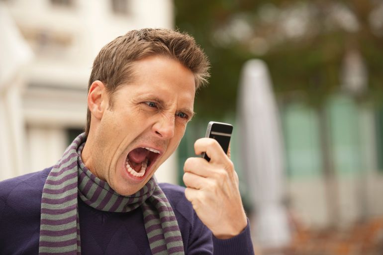Germany, Bavaria, Munich, Man holding mobile phone, screaming, portrait