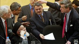 US civilian Administrator in Iraq Paul Bremer (R) gestures to Mohammed Bahr al-Uloum, President of the 25-member Council (L, seated), and other officials during the meeting of the Iraqi Governing Council in Baghdad on March 8, 2004. Iraq's Governing Council signed an interim constitution on Monday, a key step towards a planned handover of sovereignty by U.S.-led occupation forces to Iraqis on June 30. REUTERS/Peter Andrews