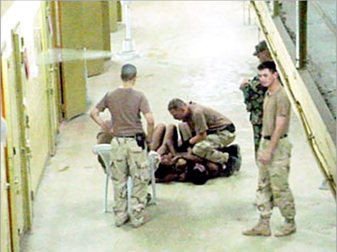 f: *MANDATORY CREDIT THE WASHINGTON POST*: An unidentified US soldier (C) at Abu Ghraib prison appears to be kneeling on naked detainees at the Abu Ghraib prison, outside of Baghdad in these undated still photos