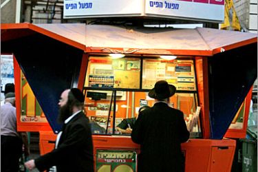 REUTERS/ An Ultra orthodox Jewish man (R) stands in front of a lottery station in Bnei Brak city, near Tel Aviv, September 28, 2005. More than 60 percent of ultra-Orthodox adults in the country