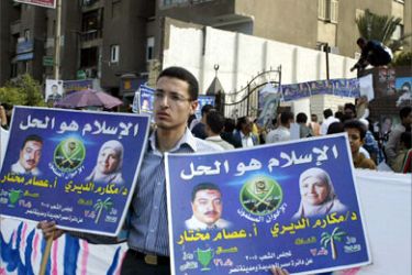 An Egyptian man holds a campaign poster of Makarem al-Deiri (R), the only woman candidate backed by Egypt's influential Muslim Brotherhood, in front of a polling station in Cairo 09 November 2005.