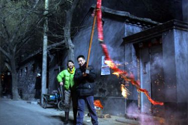 A man burns a stick of over 1,000 firecrackers during loud celebrations moments after midnight in an old Beijing neighborhood near the ancient Bell Tower, early 29 January 2006
