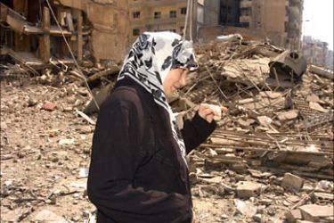 f_A woman walks at the devastated Bir al-Abed district in the southern suburbs of Beirut, 20 July 2006. Israeli bombs and missiles caused the destruction,