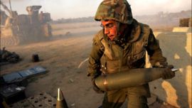 f_An Israeli soldier races to deliver a fresh 155 mm artillery shell to a mobile artillery unit as it fires on the Gaza Strip from a stretch of farmland located near the Israeli Kibbutz