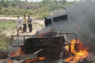 Residents watch a Polish armoured vehicle as it burns after being hit by a roadside bomb in Diwaniya, 180 km (112 miles) south of Baghdad August 7, 2007. Lieutenant-Colonel