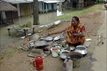 r_Kanta Das, 65, cooks beside a road after losing her home to floods on the outskirts of the northeastern Indian city of Guwahati September 11, 2007. About 10 million