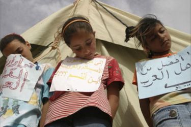 Palestinian girls with signs on their chests pretend to be hanged as they pose outside a tent during a sit-in demonstration in a refugee camp near the Iraqi-Syrian borders in Iraq, about 650 km (404 miles) west of Baghdad, April 15, 2008.