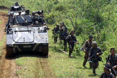 Philippine Army troops walk beside armoured vehicles as they arrive at Camp Bilal in Poona Piagapo in The Lanao del Norte Province of the southern Philippines on August 28,