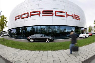 r_A man passes the store of a Porsche trader in Munich October 30, 2008. European carmakers will press their call for an EU loan of 40 billion euros