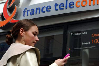 Undated file picture of a young woman checking her mobile phone in front of a France Telecom logo. The French finance ministry said Wednesday