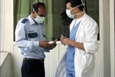 afp : A Jordanian medic wearing a mask talks to a security guard outside a hospital in Amman on June 16, 2009. Jordan has recorded its first cases of swine flu, quarantining two