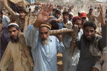 A mob of internally displaced men demand food and supply rations while carrying an injured man through the UNHCR (United Nations High Commission for Refugees) Yar Hussain camp in Swabi district, located about 120 km (75 miles) northwest of Pakistan's capital Islamabad July 13, 2009.