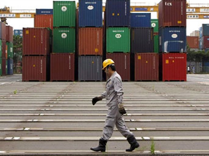 r : A worker walks in a container area at a port in Tokyo July 23, 2009. Japan's annual export slide slowed in June from May, trade data showed on Thursday, suggesting that