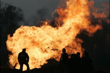 Rescuers are silhouetted against the fire rising from a gas pipe at a gas station at Rozhdestvenskaya settlement, 40 km (24.8 miles) from Russia's southern city of Stavropol, November 13, 2009.