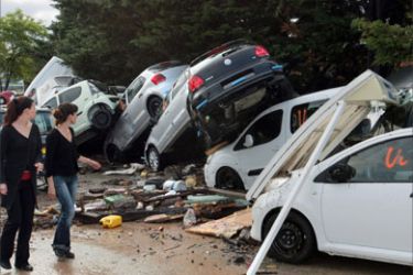 People walk by damaged cars in the aftermath of flooding in a western district of the French south eastern city of Draguignan on June 16, 2010