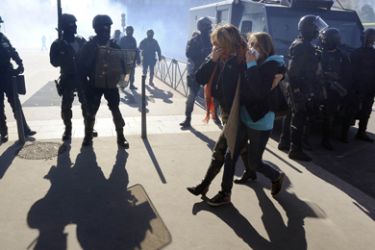 High school student walk past anti-riot police officers during a demonstration in Lyon, southern France, on October 21, 2010, to protest against the pensions reform. French protestors