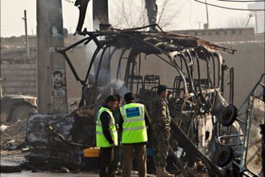 r_Investigators stand in front of a destroyed bus after a suicide attack in Kabul December 19, 2010. Five Afghan army training officers were killed and nine wounded in an attack by two Taliban