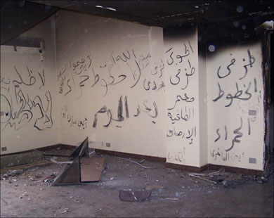 شعارات مناهضة للقذافي على جدران المنزل المحروق