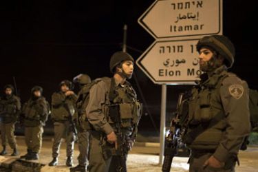 Israeli soldiers block the road in the Hawara checkpoint south of the West Bank city of Nablus on March 12,2011 after a Palestinian killed five Israelis in an overnight attack in the Jewish settlement of Itamar, in the Israeli-occupied occupied West Bank. According to media reports the vicitms were all members of the same family, including a baby and a toddler