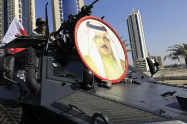 A soldier from the Gulf Cooperation Council (GCC) forces guards the entrance to Pearl Square from his armoured personnel carrier (APC) in Manama March 19, 2011. An image of Bahrain's King Hamad bin Isa al-Khalifa is seen on the front of the vehicle.