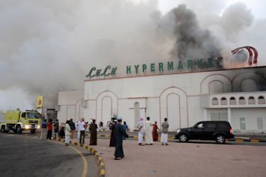 epa02607507 Smoke rises from the Lulu hypermarket in Sohar, some 250 kilometers north of Oman's capital Muscat, on 28 February 2011 after protesters allegedly set it on fire during protests calling for political reforms.