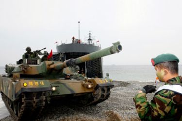 A South Korean marine (R) guides its tank landing from a naval vessel during its annual landing exercise against possible attacks from North Korea at a seashore in Pohang, about 370 km (231 miles) southeast of Seoul, May 19, 2011.