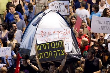 f_Israelis holds-up banners as they march in the centre of the coastal city of Tel Aviv on July 30, 2011, to protest against rising housing prices and social inequalities in the Jewish state