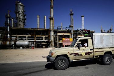 f_Libyan rebels drive past the Zawiya oil refinery, some 40 kms west of Tripoli, on August 19, 2011 after taking complete control of the key oil refinery that is the only source of fuel to the capital, its manager said. AFP