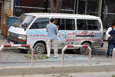 Journalists stand near a bullet-ridden mini-van during an on-going attack in Kabul city centre on September 13, 2011. The Taliban launched a major attack in the centre of Kabul, hitting NATO's coalition force headquarters next to the US embassy