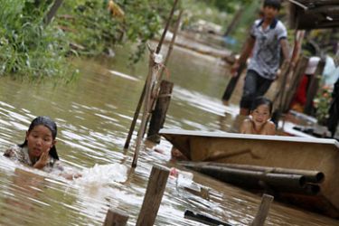 r_A woman (L) bathes in flood waters in Kandal province October 11, 2011. Monsoon rains, floods and landslides have killed 207 people in Cambodia since August 13