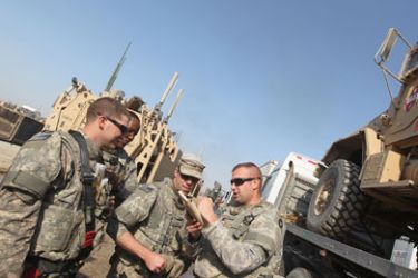 US soldiers chat next to trucks loaded with military vehicles and equipment as part of preparations to leave their military base at Camp Victory on the outskirts of the Iraqi capital Baghdad and head to neighbouring Kuwait on November 20, 2011. US forces are due leave Iraq by the end of this year, bringing to a close an almost nine-year war that has left thousands of US soldiers and tens of thousands of Iraqis dead, and cost hundreds of billions of dollars.