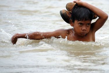 A boy carrying his shoes crosses the Kapay river, one of the three rivers that overflowed during the path of typhoon Washi, in a remote area in Iligan City, southern Philippines