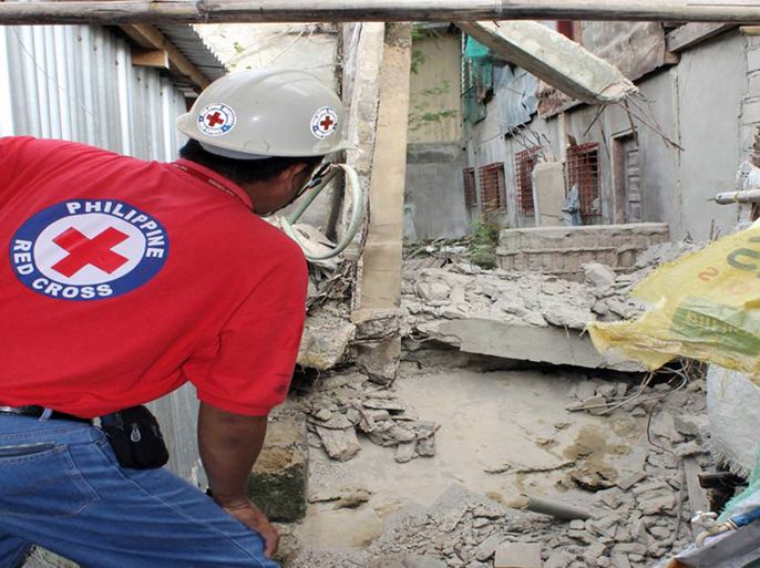This image released by Philippine National Red Cross (PNRC) on March 6, 2012, shows a PNRC employee (L) inspecting a damaged concrete structure next to houses after a 5.2 magnitude earthquake hit Masbate City, Central Philippines. A 5.2-magnitude earthquake rocked the central Philippines early on March 6, breaking windows, destroying an old abandoned building and provoking widespread panic among residents, officials said.
