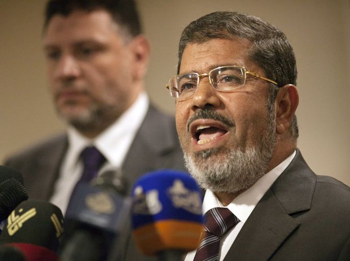 Muslim Brotherhood Egyptian presidential candidate Mohammed Mursi (2nd L) talks with an aid during a press conference in Cairo on May 26, 2012. The Muslim Brotherhood today urged Egyptians to rally behind their presidential candidate in an almost certain run-off with rival Ahmed Shafiq, warning the country would be in danger if fallen dictator Hosni Mubarak's premier wins. AFP