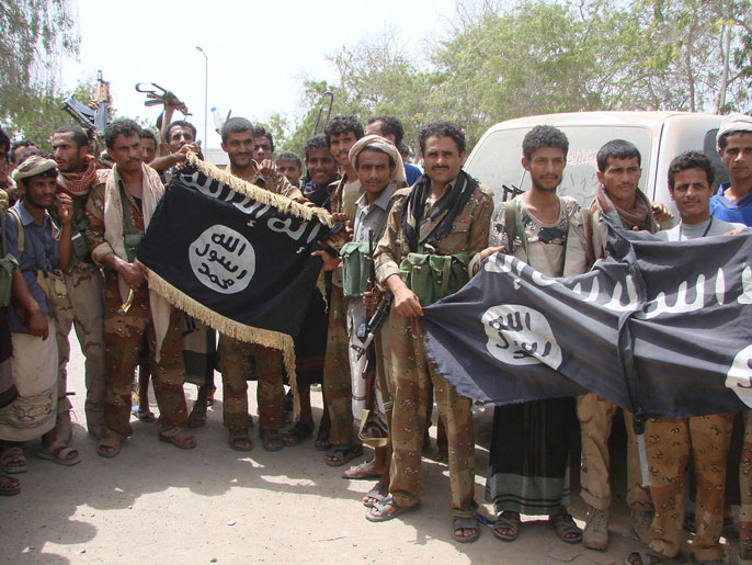جنود يمنيون يستعرضون رايات أنصار الشريعة بعد إخراجهم من موقع بزنجبار (رويترز-أرشيف)