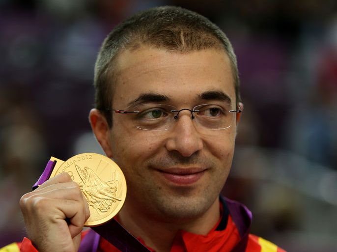 Romania's Alin George Moldoveanu shows his gold medal on the podium after winning the men's 10m air rifle during the London 2012 Olympic Games at the Royal Artillery Barracks in London on July 30, 2012. AFP PHOTO/MARWAN NAAMANI