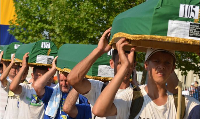 Bosnian Muslims carry caskets with the remains of their relatives before a mass burial ceremony for 520 Srebrenica massacre victims, at the Potocari Memorial Center, on July 10, 2012. Tens of thousands of people are expected in Potocari on July 11 to commemorate the 17th anniversary of the moment the UN-protected enclave fell to Bosnian Serb troops. The remains of 520 people will be buried alongside the 5,137 victims of the massacre already interred in the vast cemetery which faces the former UN army base. Some 8,000 Muslim men and boys were killed in just a few days after the eastern town under UN protection was captured by Bosnian Serb forces 17 years ago. AFP PHOTO