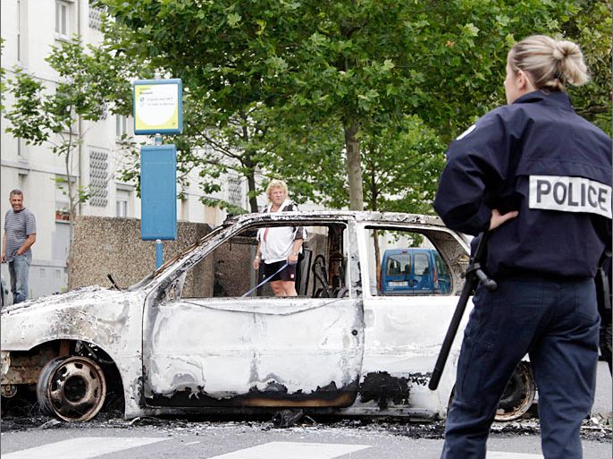 French police stand guard near a car destroyed in overnight clashes where gangs of youths set cars and buildings ablaze in Amiens August 14, 2012. About 100 youths burned cars, a leisure centre and a nursery school according to an official from the prefect's office. REUTERS/Pascal Rossignol (FRANCE - Tags: CRIME LAW CIVIL UNREST)