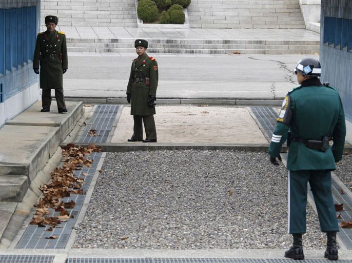 North Korean soldiers look across a concrete border as a South Korean soldier (R) stands guard at the truce village of Panmunjom in the Demilitarised Zone (DMZ), in Paju, 55 km (34 miles) north of Seoul December 2, 2011. DMZ is the 4-km wide buffer that runs along the heavily armed military border. The border was framed by a truce signed at Panmunjom that suspended the 1950-53 Korea War, which pitted U.S.-led U.N. forces and South Korea against North Korean and Chinese troops.