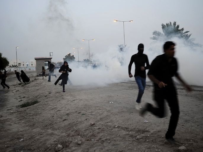 -, BAHRAIN : Bahraini Shiite Muslim protestors run for cover from tear gas fired by riot police during clashes following religious ceremonies commemorating Ashura, in the village of Daih, west of the capital Manama, on November 26, 2012. The United States said last week that it was concerned about rising violence in its Arab ally Bahrain, and urged the government to exercise "restraint" in responding to protests. AFP PHOTO/MOHAMMED AL-SHAIKH