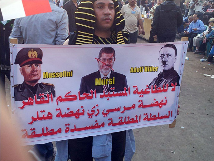 متظاهر يلبس الزي الفرعوني ويحمل لافتة تشبه مرسي بهتلر (الجزيرة نت)