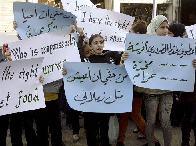 Palestinian girls, whose families fled the Yarmuk Palestinian refugee camp in the Syrian capital of Damascus, holds up a sign during a rally in front on the United Nations Relief and Works Agency (UNRWA) offices in the Palestinian refugee camp of Ain El-Helweh on the outskirts of the southern Lebanese city of Sidon, on December 18, 2012. In Damascus, Palestinian refugees fled as blasts and fierce clashes between rebels and pro-Syrian regime Popular Front for the Liberation of Palestine-General Command (PFLP-GC) rocked the Yarmuk camp overnight, a day after President Bashar al-Assad's deputy gave a gloomy assessment of Syria's brutal conflict. AFP PHOTO/MAHMOUD ZAYYAT