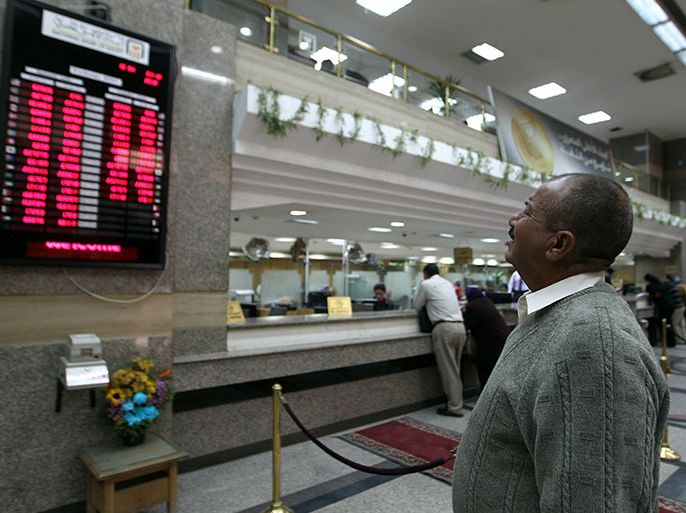 epa03520919 A man checks a currency board, in a bank, Cairo, Egypt, 31 December 2012. Reports state Egyptian President Mohamed Morsi said on 30 December, the market will stabilize within days after the Egyptian pound has declined against the dollar, and that the government has moved towards balancing the market. Recently Credit-rating agency Standard & Poor's cut Egypt's long-term rating to B-. Egypt is still waiting for a the upcoming IMF loan of 4.8 Billion Dollars. EPA/KHALED ELFIQI