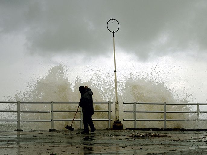 A man cleans the sidewalk next to the shore of the southern Lebanese city of Sidon, on January 8, 2013. Stormy weather, including high winds and heavy rainfall, lashed the eastern Mediterranean coast, downing power lines and trees and causing several injuries in a number of countries. AFP PHOTO / MAHMOUD ZAYYAT