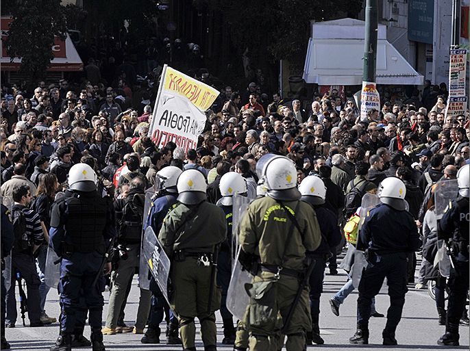 Police stand guard while thousands of protesters march in central Athens during a 24-hour-general strike on February 20, 2013. Thousands of Greeks joined new anti-austerity protests on February 20, causing massive disruption to flights, ferries and hospital services in the debt-ridden country's first general strike this year. About 15,000 protesters took part in a Communist-organised demonstration in Athens and 20,000 more joined protests organised by other unions, according to police figures. AFP PHOTO / LOUISA GOULIAMAKI