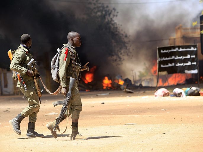Malian soldiers cross a street as they fight while clashes erupted in the city of Gao on February 21, 2013 and an apparent car bomb struck near a camp housing French troops as Malian and foreign forces struggled to secure Mali's volatile north against Islamist rebels. AFP PHOTO / FREDERIC LAFARGUE