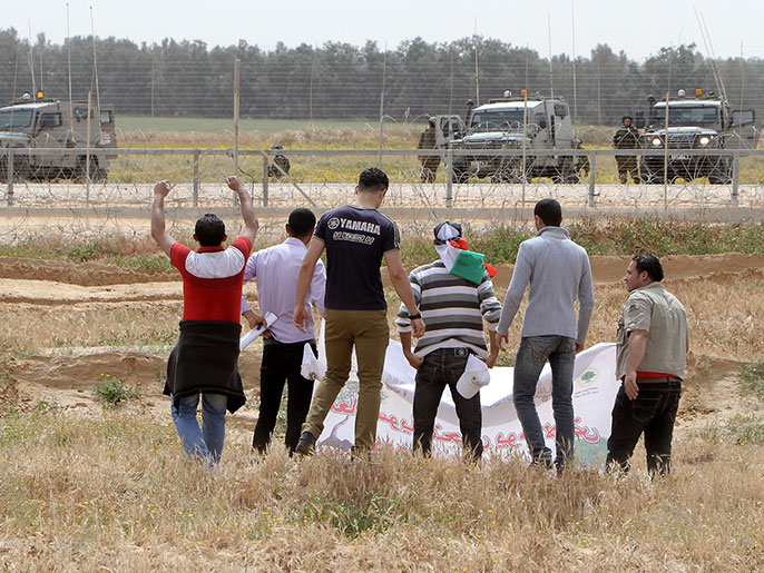 ‪فلسطينيون يحتجون في يوم الأرض قرب السياج الحدودي في قطاع غزة‬ (الفرنسية)