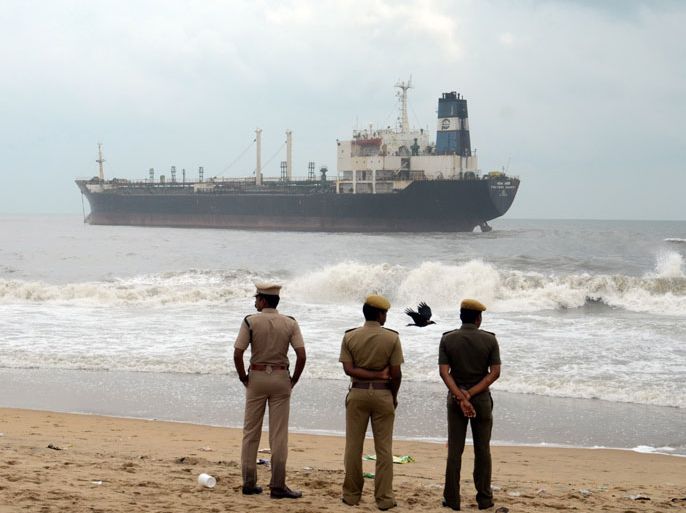 epa03454299 Indian policemen stand to watch the oil tanker ship 'Pratibha Cauvery' in Chennai, India, 01 November 2012. One crew member of this oil tanker that ran aground off Chennai died and five others were missing after the cyclone Nilam that hit India's south-eastern coast before it weakened, news reports said. EPA/NATHAN G