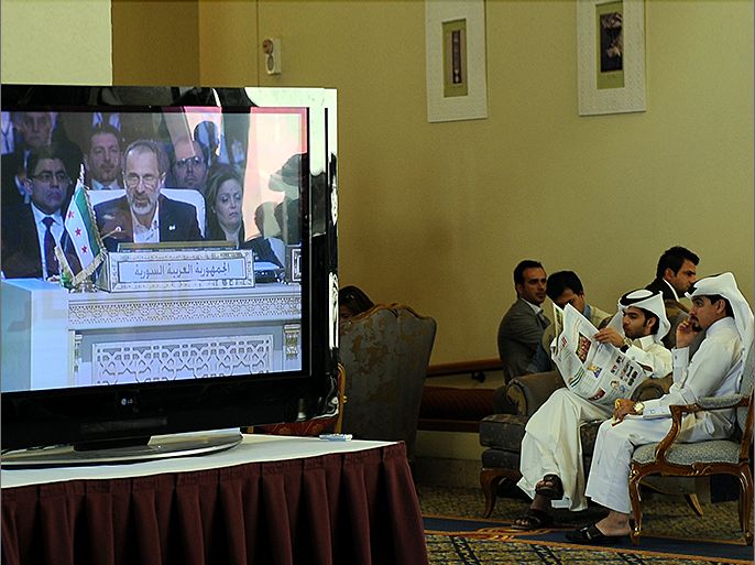epa03640916 Members of the media watch live in TV Syrian National Coalition (SNC) President Mouaz al-Khatib, during a live address at the opening of the Arab League summit in Doha, Qatar, 26 March 2013. The Syrian opposition was on 26 March handed Syria's seat in the Arab League. National Coalition leader Moaz al-Khatib and a small delegation were in attendance at the annual summit of the 22-member pan-Arab grouping. EPA/STR