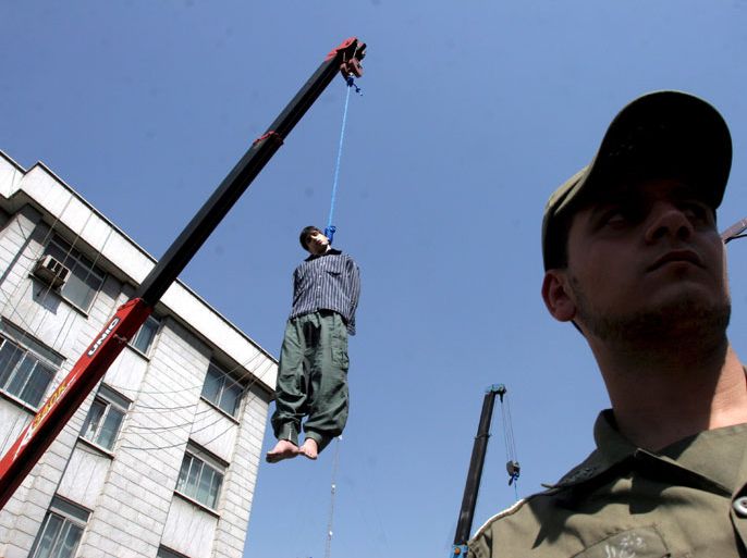 epa01082595 An Iranian soldier stands under the body of Hossein Kavousii (L) during his public execution on 02 August 2007 in Tehran, Iran. Two convicted murderers were hanged publicly in Tehran in the latest in a wave of executions across Iran. Majid K and his nephew Hossein, who had been convicted of murdering deputy general prosecutor Massoud Moqadass in August 2005, were executed using nooses tied to a crane arm mounted on the back of a truck. Hundreds of people witnessed the hanging held in northern Tehran. Convicts are executed in the same city and district where the crime was committed. EPA/ABEDIN TAHERKENAREH EDITORS NOTE GRAPHIC CONTENT